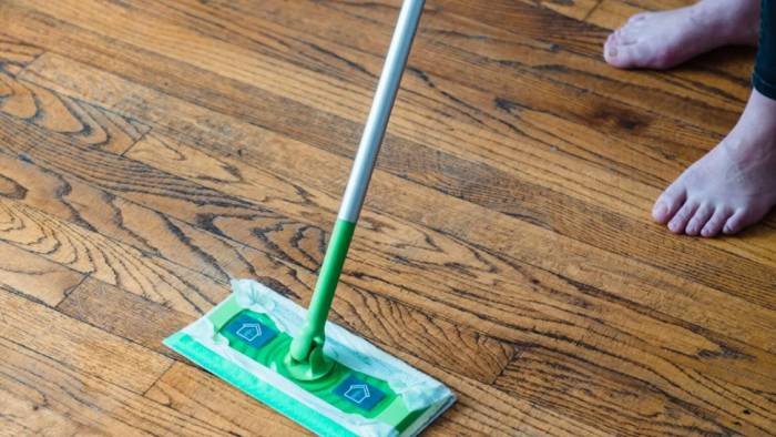 Person mopping and cleaning a tiled floor to achieve a spotless and shiny surface
